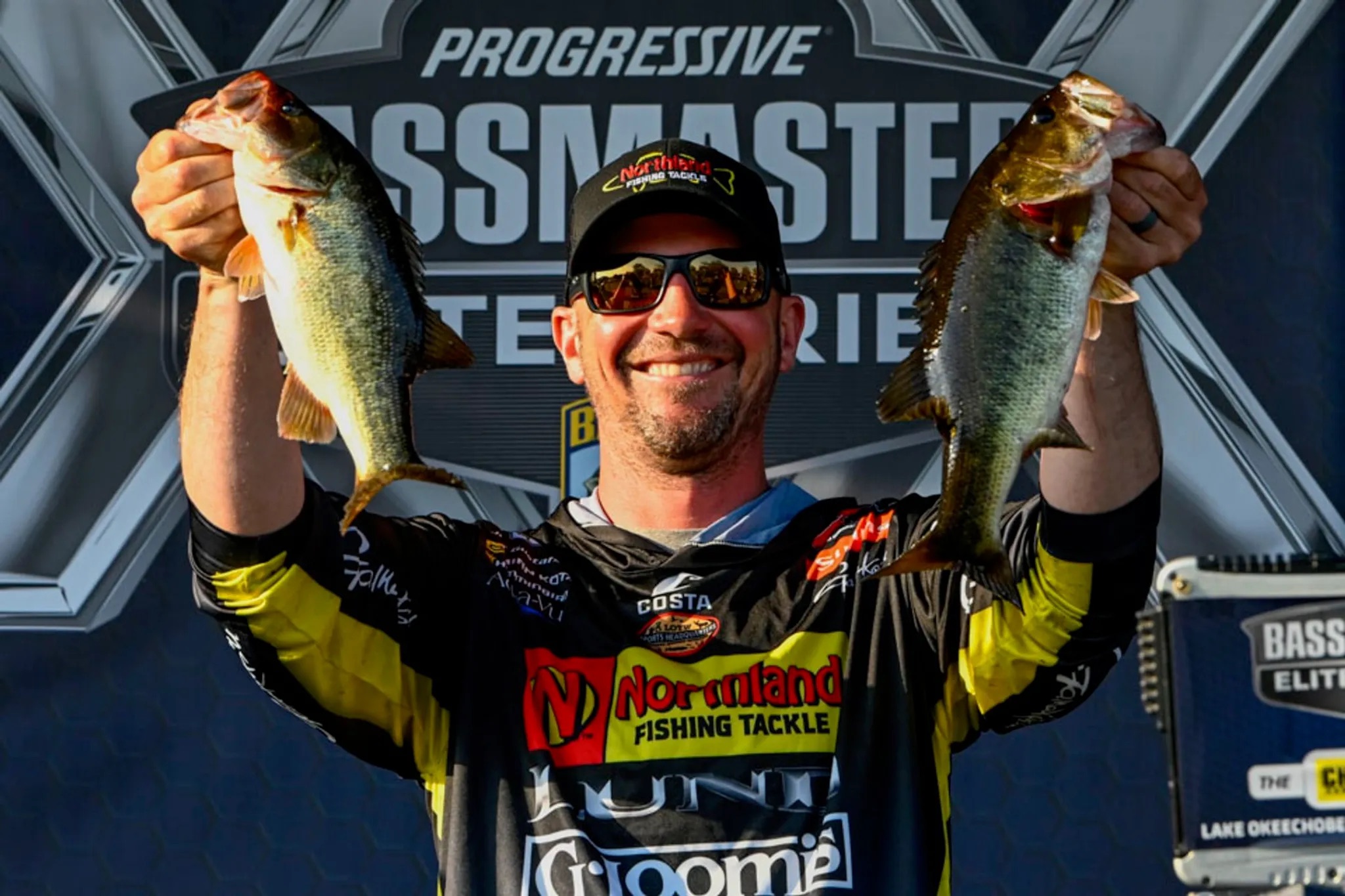 Angler holding two fish at the Progressive Bassmaster Elite Series.