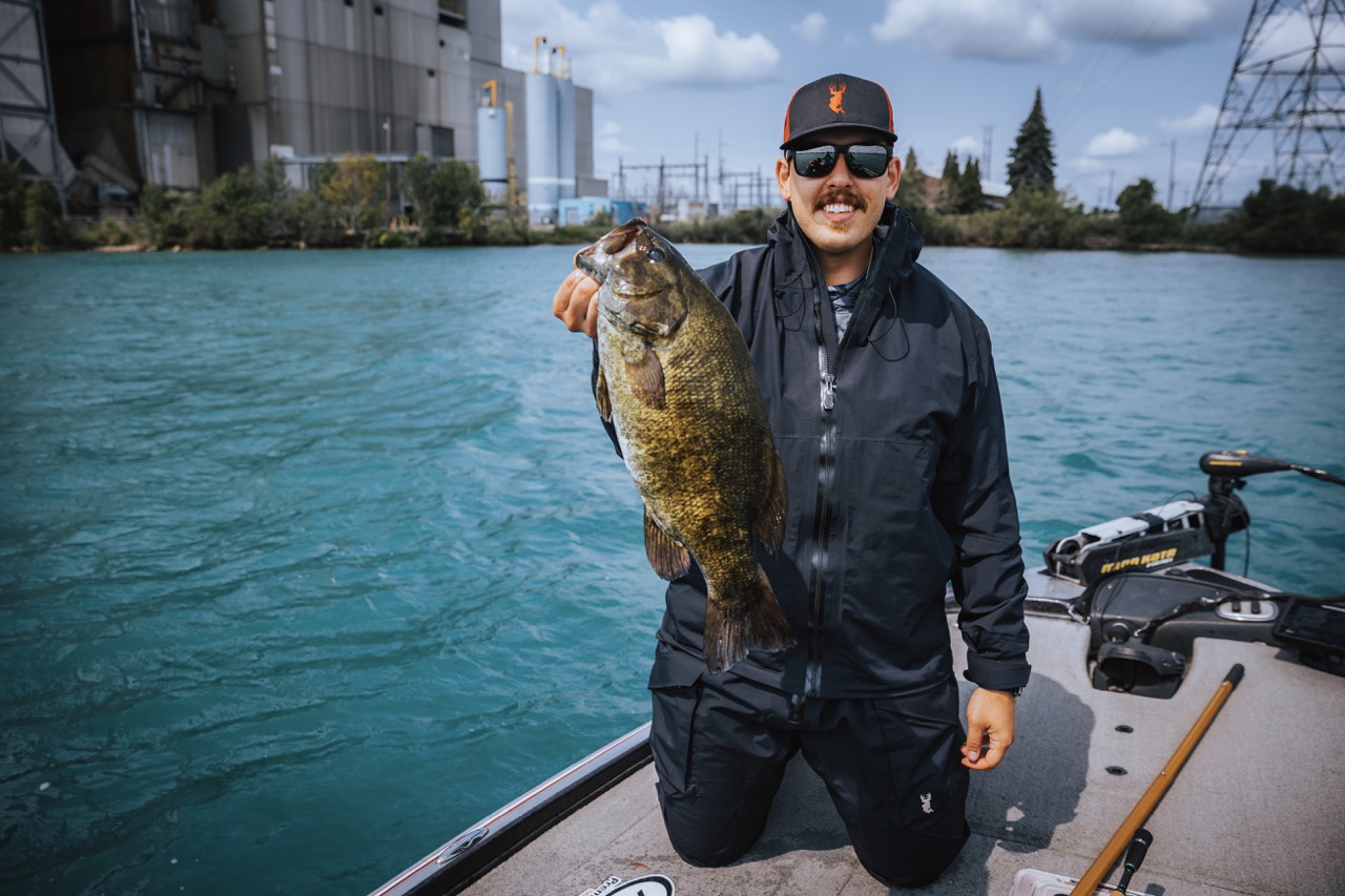 An angler on the water, holding up a largemouth bass.
